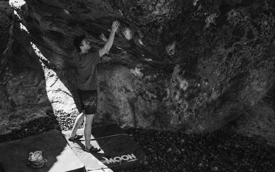 Black-and-white photograph of a climber beneath a rock face